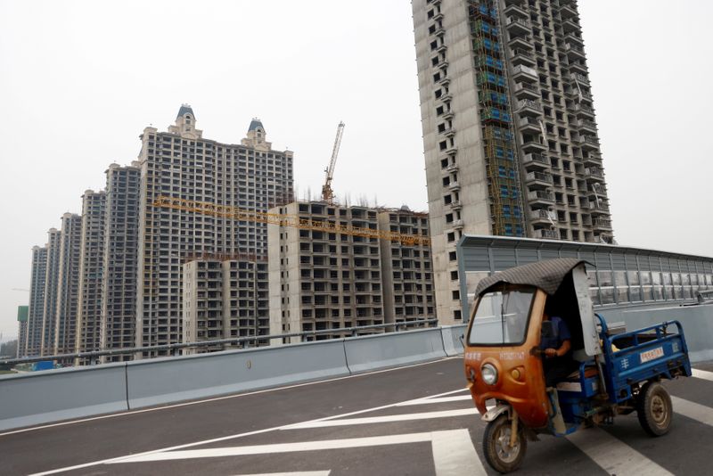 © Reuters. FILE PHOTO: A vehicle drives past unfinished residential buildings at Evergrande Oasis, a housing complex developed by Evergrande Group, in Luoyang, China September 16, 2021. REUTERS/Carlos Garcia Rawlins/File Photo