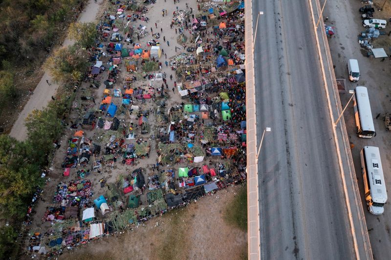&copy; Reuters. FILE PHOTO: Vehicles await to transport migrants as they shelter along the Del Rio International Bridge after crossing the Rio Grande river into the U.S. from Ciudad Acuna in Del Rio, Texas, U.S. September 19, 2021. Picture taken with a drone. REUTERS/Adr