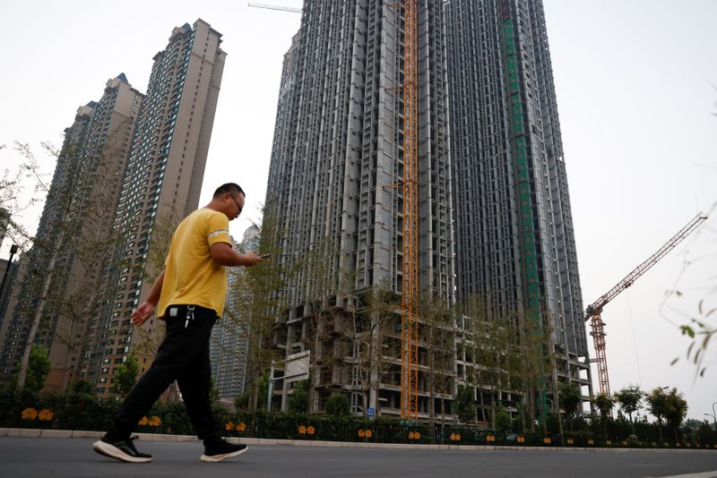&copy; Reuters. FILE PHOTO: A man walks in front of unfinished residential buildings at the Evergrande Oasis, a housing complex developed by Evergrande Group, in Luoyang, China September 15, 2021. REUTERS/Carlos Garcia Rawlins