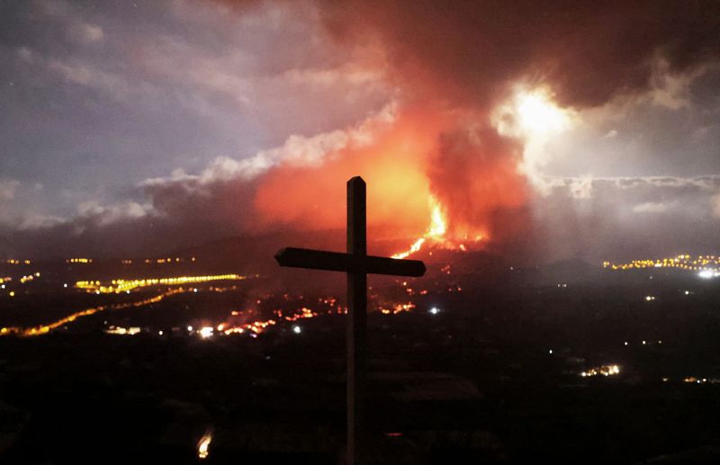 &copy; Reuters. A cross is seen as lava and smoke rise following the eruption of a volcano on the Island of La Palma, in Los Llanos de Aridane, Spain September 21, 2021. REUTERS/Nacho Doce