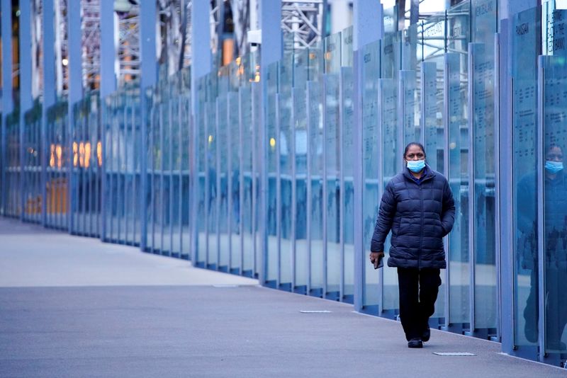 &copy; Reuters. A woman wearing a protective face mask walks along a deserted city bridge during morning commute hours on the first day of a lockdown as the state of Victoria looks to curb the spread of a coronavirus disease (COVID-19) outbreak in Melbourne, Australia, J