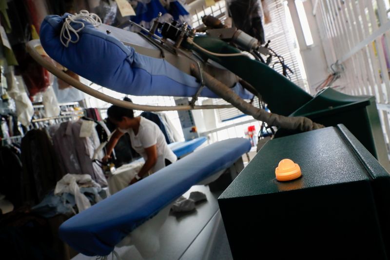 &copy; Reuters. The light on a steam machine is on as Gladys Mariscal Medina irons while working at the dry cleaner's she helps manage in Madrid, Spain, September 21, 2021. REUTERS/Susana Vera