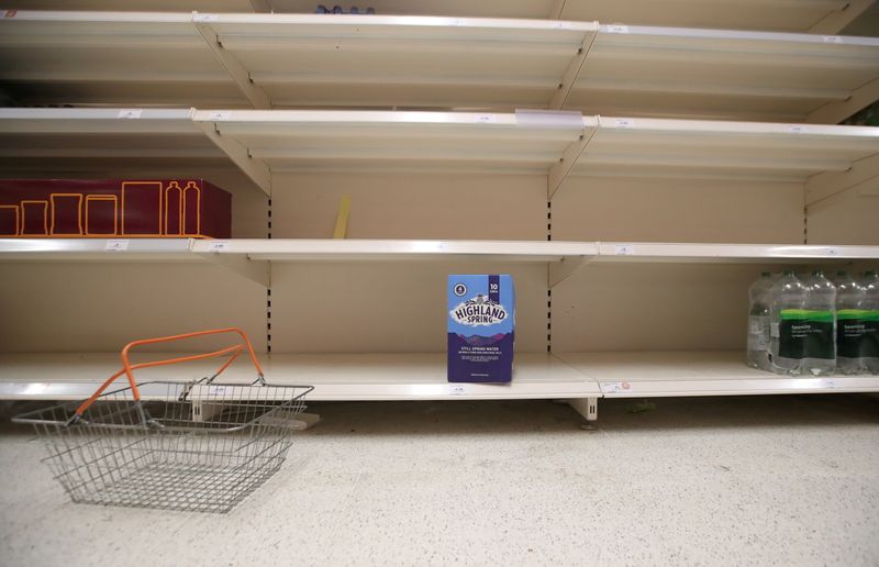 © Reuters. FILE PHOTO: A shopping basket is discarded next to empty shelves of the soft drinks aisle, in Sainsbury's supermarket in Harpenden, Britain, September 22, 2021.  REUTERS/Peter Cziborra     