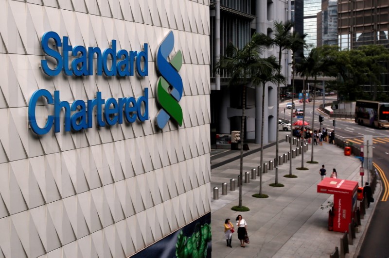 &copy; Reuters. FILE PHOTO: People walk outside the main branch of Standard Chartered in Hong Kong, China August 1, 2017. REUTERS/Bobby Yip/File Photo