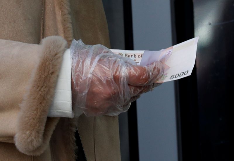 &copy; Reuters. FILE PHOTO: A woman wearing a plastic glove holds money as she stands in a queue to buy face masks at a post office, after a shortage of masks amid the rise in confirmed cases of the novel coronavirus disease COVID-19, in Daegu, South Korea, March 4, 2020