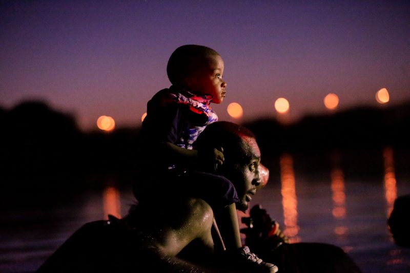 &copy; Reuters. A migrant seeking refuge in the U.S. crosses the Rio Grande river with his son on shoulders, at the border towards Del Rio, Texas, U.S., as seen from Ciudad Acuna, Mexico, September 23, 2021. REUTERS/Daniel Becerril