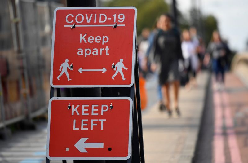&copy; Reuters. Pedestrians walk near public health signs, whilst the reproduction "R" number of COVID-19 infections in the United Kingdom has risen and may be above 1, the Government Office for Science said on Friday, indicating a risk that the overall epidemic is growi