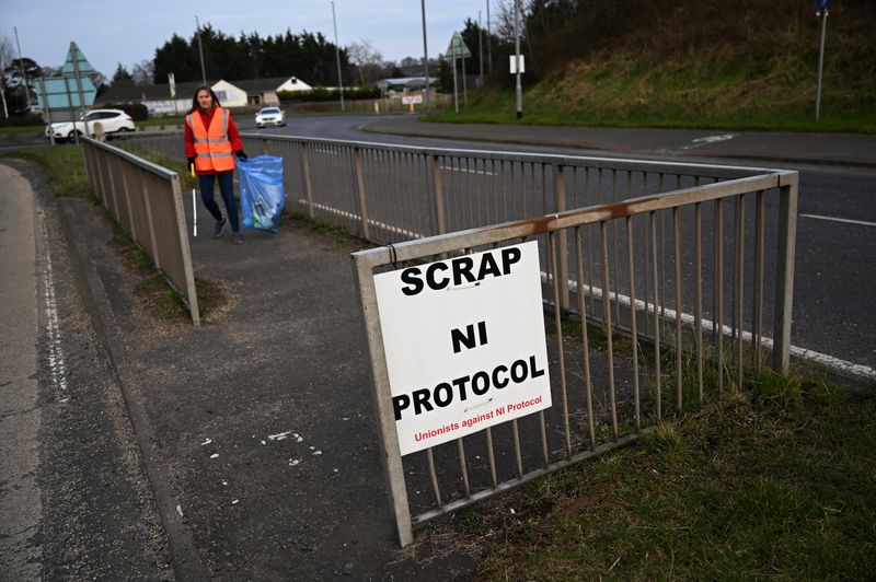 &copy; Reuters. A City worker collects rubbish on a road median featuring a sign reading 'Scrap NI protocol' near the Port of Larne, Northern Ireland, March 6, 2021.  REUTERS/Clodagh Kilcoyne