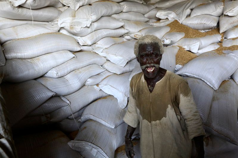 &copy; Reuters. عامل يبتسم أثناء نقل أجولة من القمح في ميناء بورتسودان في السودان. صورة من أرشيف رويترز..  