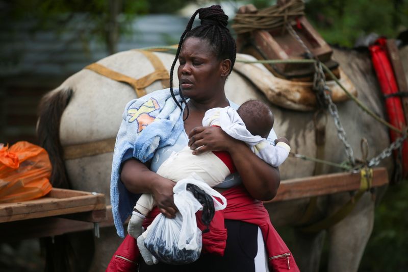 &copy; Reuters. Una migrante sostiene a un niño mientras se prepara para cruzar a Panamá y continuar hacia el norte, en Acandí, Colombia. 23 de septiembre de 2021. REUTERS/Luisa Gonzalez
