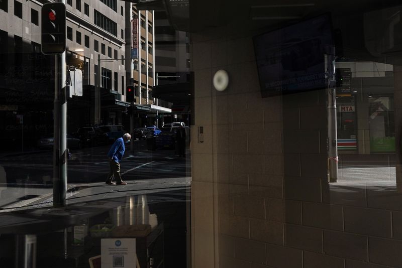&copy; Reuters. FILE PHOTO: A pedestrian in a protective face mask, seen reflected in the window of a closed cafe, walks through the city centre during a lockdown to curb the spread of a coronavirus disease (COVID-19) outbreak in Sydney, Australia, September 24, 2021.  R