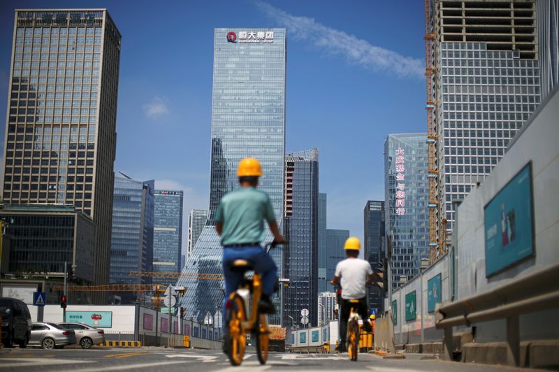 &copy; Reuters. FOTO DE ARCHIVO-Hombres pasan en bicicleta por delante de unas obras de construcción cerca de la sede de China Evergrande Group en Shenzhen, provincia de Cantón, China. 26 de septiembre de 2021. REUTERS/Aly Song