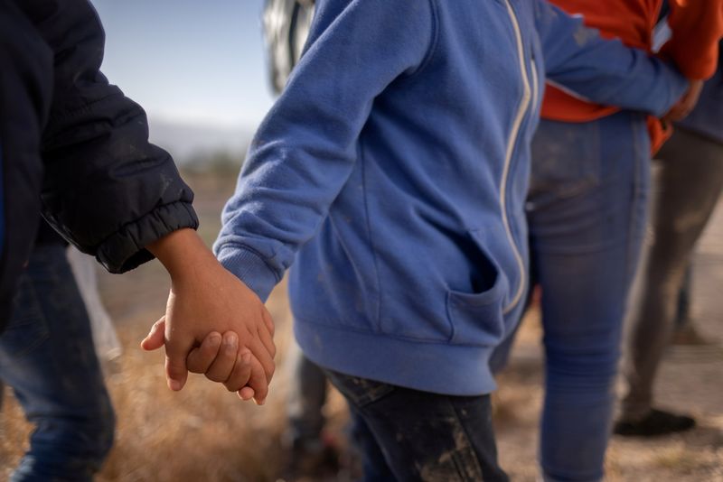 &copy; Reuters. Asylum seeking unaccompanied minors hold hands amid adult migrants from Central America as they await transport after crossing the Rio Grande river into the United States from Mexico on a raft in Penitas, Texas, U.S., March 12, 2021. The unrelated minors,