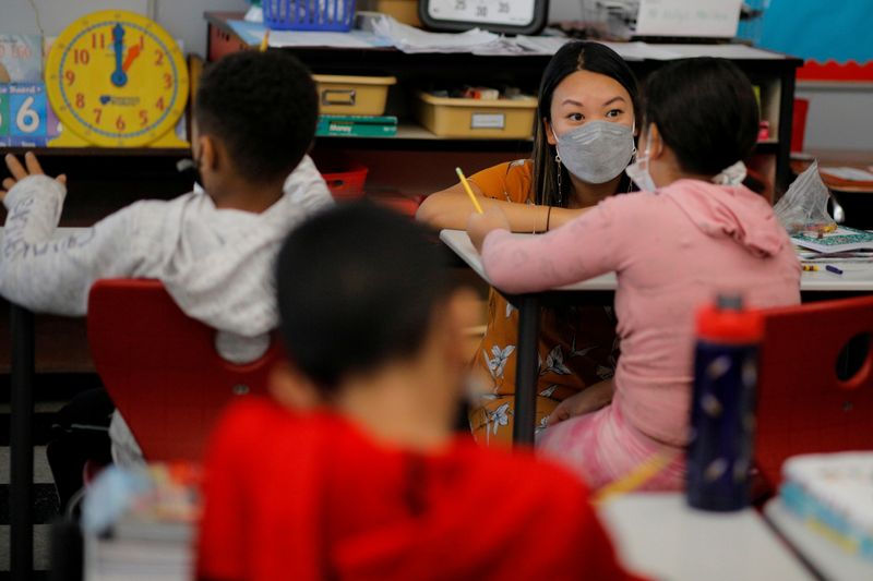 © Reuters. FILE PHOTO: Teacher Mary Yi works with a fourth grade student at the Sokolowski School, where students and teachers are required to wear masks because of the coronavirus disease (COVID-19) pandemic, in Chelsea, Massachusetts, U.S., September 15, 2021. REUTERS/Brian Snyder