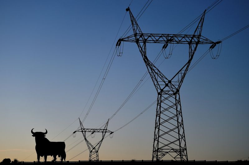 &copy; Reuters. Líneas eléctricas que conectan torres de alta tensión y una figura de un toro del tamaño de una valla publicitaria se ven al atardecer en El Berrón