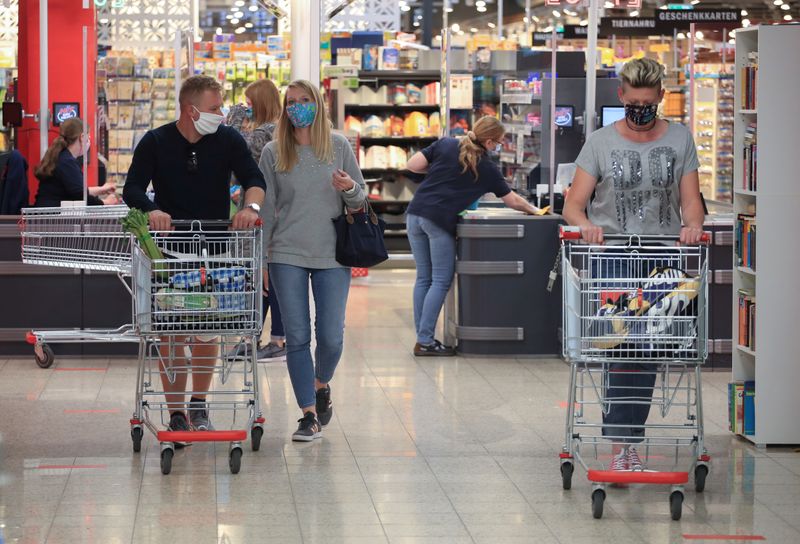 &copy; Reuters. FILE PHOTO: People wearing face masks leave a supermarket, after the federal state of North Rhine-Westphalia decided to make wearing protective masks obligatory in shops and public transportation to fight the spread of the coronavirus disease (COVID-19), 