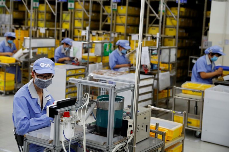 © Reuters. FILE PHOTO: Employees wearing face masks work at a factory of the component maker SMC during a government organised tour of its facility following the outbreak of the coronavirus disease (COVID-19), in Beijing, China May 13, 2020. REUTERS/Thomas Peter/File Photo