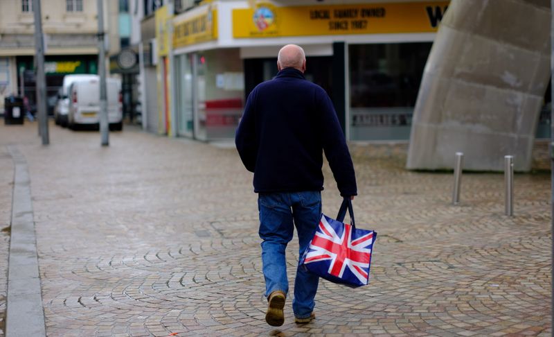 &copy; Reuters. A man carries a Union Jack themed shopping bag as he walks along an empty shopping street in Blackpool, Britain, March 9, 2021. REUTERS/Phil Noble