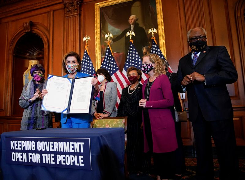 © Reuters. U.S. House Speaker Nancy Pelosi (D-CA) is flanked by members of the House Democratic Caucus as she holds the continuing resolution she signed to avoid a U.S. government shutdown during a bill enrollment ceremony on Capitol Hill in Washington, U.S., September 30, 2021. REUTERS/Elizabeth Frantz