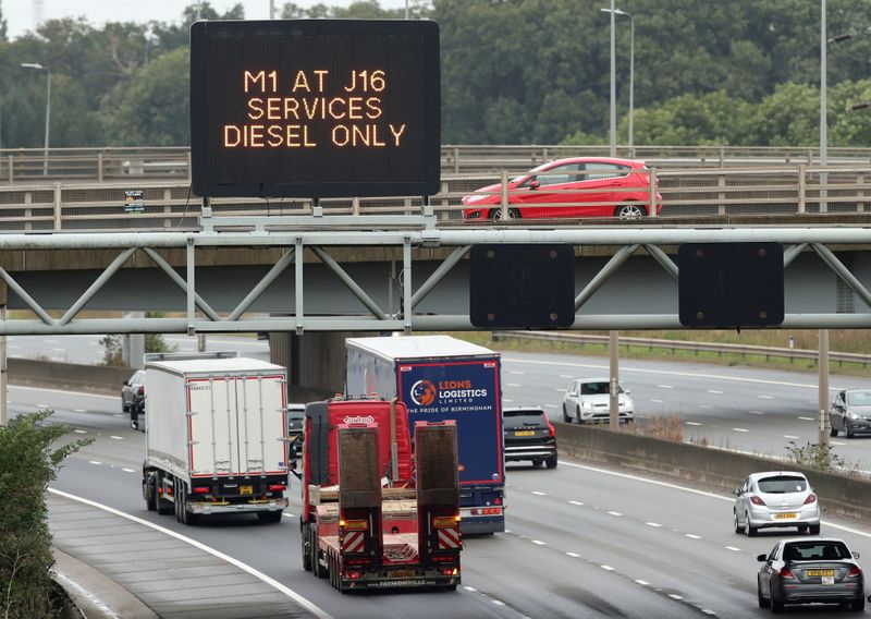 &copy; Reuters. FILE PHOTO: Lorries drive past a fuel warning sign on the M1 motorway amid a fuel shortage, in Luton, Britain, September 30, 2021. REUTERS/Peter Cziborra/File Photo