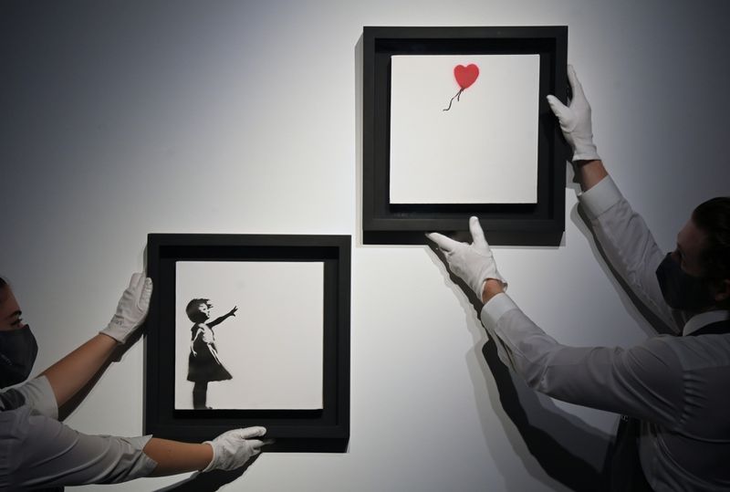 &copy; Reuters. Art handlers Becky and Adam view "Girl With Balloon" diptych by British artist Banksy, which forms part of the upcoming auction on October 15 at Christie's, "20th/21st Century: Evening Sale Including Thinking Italian,"in London, Britain, October 1, 2021. 