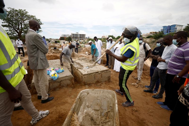 &copy; Reuters. FILE PHOTO: Grave diggers bury a man who, according to his son, died from the coronavirus disease (COVID-19) as Senegal records more COVID-19 deaths, at the Christian Saint-Lazare Cemetery in Dakar, Senegal August 4, 2021. REUTERS/Zohra Bensemra