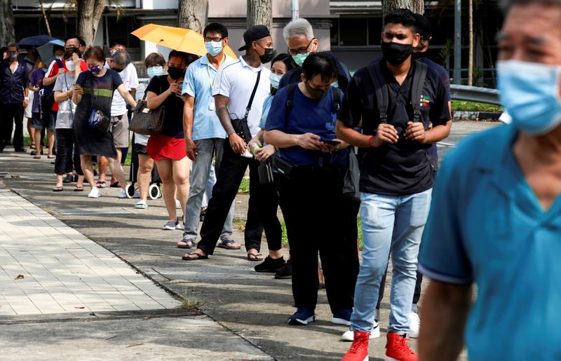 &copy; Reuters. FILE PHOTO: People queue up outside a quick test centre to take their coronavirus disease (COVID-19) antigen rapid tests, in Singapore September 21, 2021. REUTERS/Edgar Su/File Photo