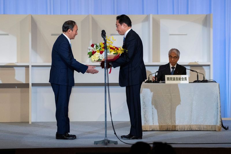 &copy; Reuters. رئيس الوزراء الياباني المنتهية ولايته يوشيهيدي سوجا يتلقى باقة زهور من رئيس الوزراء‭ ‬المقبل فوميو كيشيدا في طوكيو يوم 29 سبتمبر أيلول 2021. 