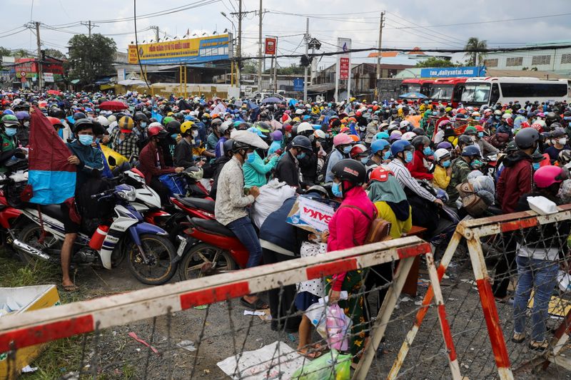 &copy; Reuters. People, mostly migrant workers who are planning to return to their hometowns, wait at a checkpoint to leave Ho Chi Minh City, Vietnam October 1, 2021. Picture taken October 1, 2021. REUTERS/Stringer 