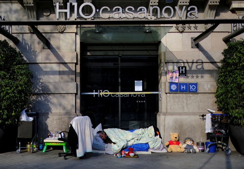 &copy; Reuters. FILE PHOTO: A homeless man sleeps on a mattress next to his belongings at the entrance of a closed hotel, after Catalonia's government imposed new restrictions in an effort to control the outbreak of the coronavirus disease (COVID-19) in Barcelona, Spain 