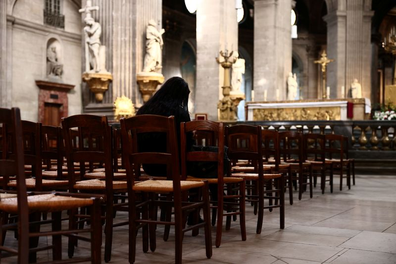 © Reuters. امرأة تجلس في كنيسة بباريس يوم الاثنين. تصوير: سارة ميسونييه - رويترز