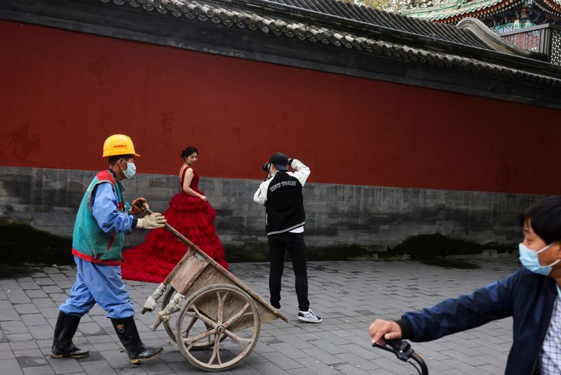 © Reuters. امرأة ترتدي زي العرس وتلتقط صورة قرب المدينة المحرمة في بكين يوم الثلاثاء في ظل انتشار فيروس كورونا. تصوير:رويترز.