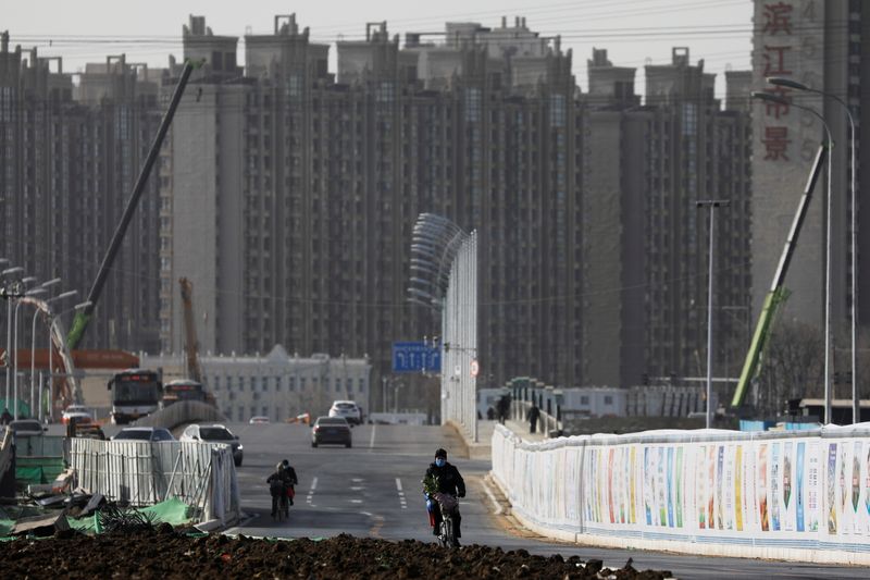 © Reuters. FILE PHOTO: A man rides a bicycle next to a construction site near residential buildings in Beijing, China, January 13, 2021. Picture taken January 13, 2021. REUTERS/Tingshu Wang/File Photo