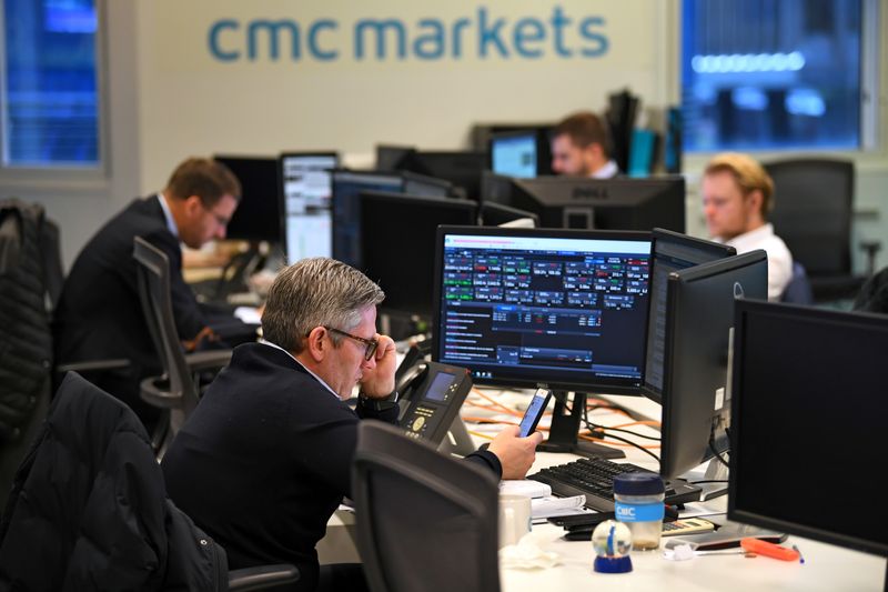 © Reuters. FILE PHOTO: Dealers work at their desks whilst screens show market data at CMC Markets in London, Britain, January 30, 2019. REUTERS/Dylan Martinez/File Photo