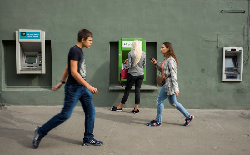 &copy; Reuters. FILE PHOTO: A woman uses an ATM machine as people walk past in central Kharkiv, Ukraine September 18, 2018. Picture taken September 18, 2018.  REUTERS/Gleb Garanich