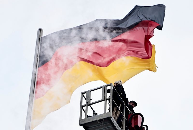 &copy; Reuters. Alcuni operai davanti a una bandiera tedesca in cima all'edificio del Reichstag a Berlino, Germania, 28 settembre 2021. REUTERS/Hannibal Hanschke
