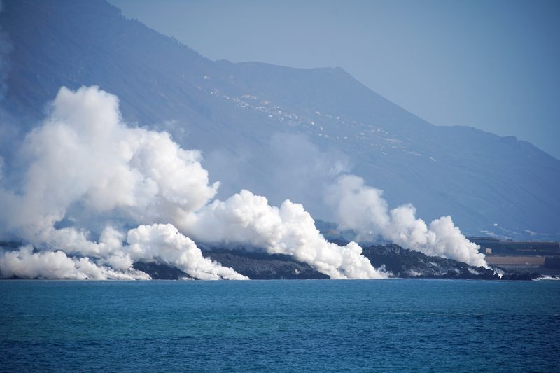 &copy; Reuters. El humo se eleva mientras la lava fluye hacia el mar después de la erupción de un volcán, vista desde el puerto de Tazacorte, isla canaria de La Palma, España, 6 de octubre de 2021. REUTERS/Juan Medina, España, 6 de octubre de 2021. REUTERS/Juan Medi