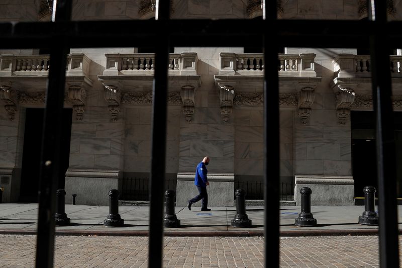 © Reuters. FILE PHOTO: A trader wearing a protective face mask walks, as the global outbreak of the coronavirus disease (COVID-19) continues, at the New York Stock Exchange (NYSE) in the financial district of New York, U.S., November 19, 2020. REUTERS/Shannon Stapleton