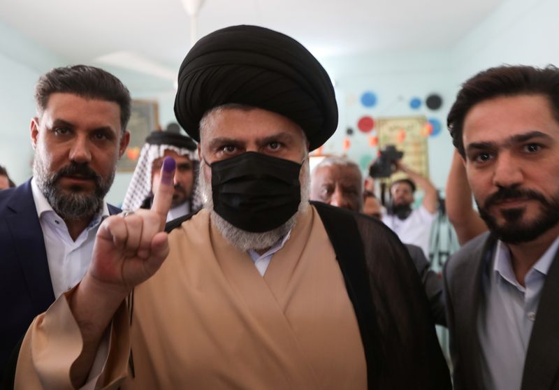 &copy; Reuters. رجل الدين العراقي الشيعي مقتدى الصدر يرفع إصبعه الملطخ بالحبر بعد إدلائه بصوته في الانتخابات العامة في مركز اقتراع بالنجف يوم الأحد. تصوير: 