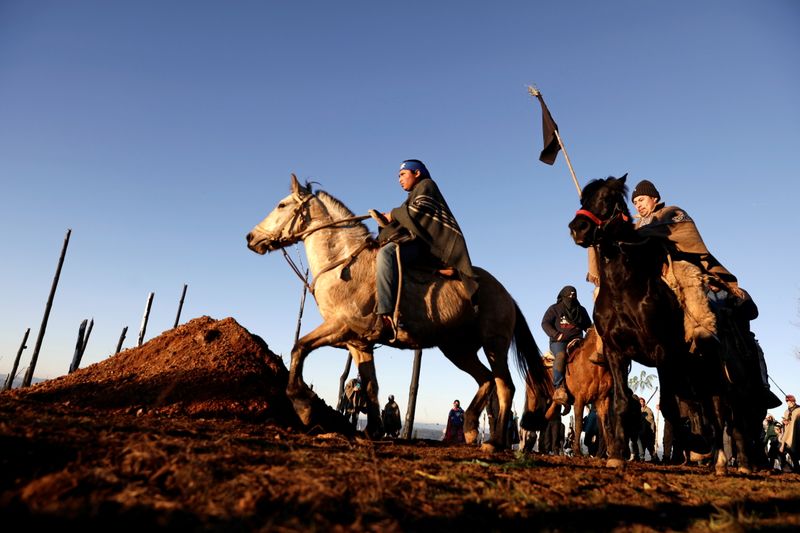 &copy; Reuters. FOTO DE ARCHIVO-Weichafes (guerreros mapuches) montan sus caballos alrededor de la tumba donde su compañero Pablo Marchant, muerto a tiros por la policía chilena, será enterrado en Lumaco, en la Araucanía, Chile. 13 de julio de 2021. REUTERS/Juan Gonz