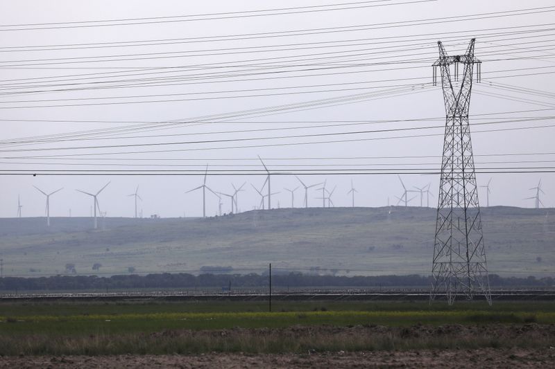 &copy; Reuters. FILE PHOTO: An electricity pylon and powers lines are seen against a backdrop of wind turbines in Zhangjiakou, Hebei province, China July 15, 2021. REUTERS/Tingshu Wang