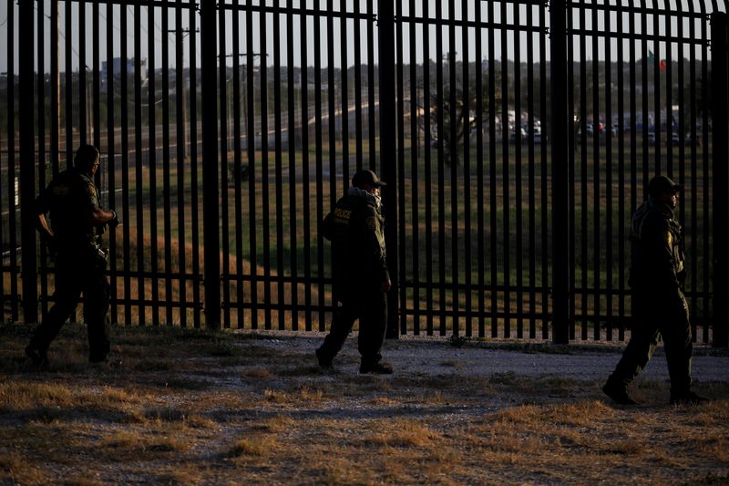 &copy; Reuters. FILE PHOTO: U.S. Border Patrol officers walk along the perimeter fence near the International Bridge between Mexico and the U.S., where migrants seeking asylum in the U.S. are waiting to be processed, in Del Rio, Texas, U.S., September 20, 2021. REUTERS/M