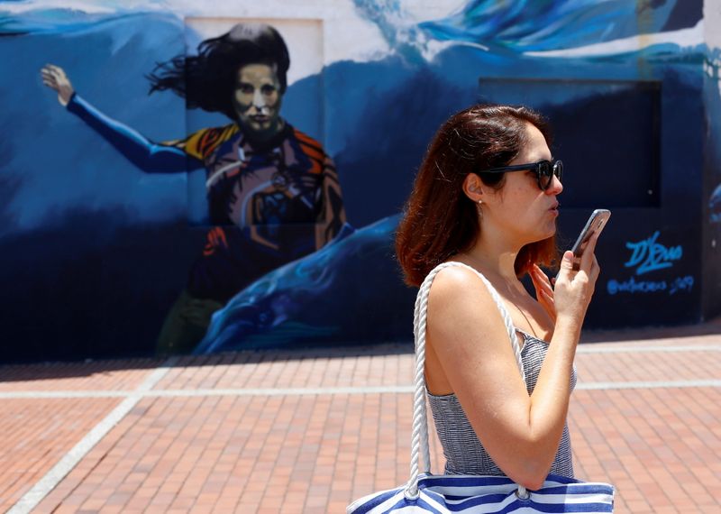 &copy; Reuters. FILE PHOTO: A woman talks via a mobile phone while walking along the avenue of Las Canteras Beach in Las Palmas on the island of Gran Canaria, Spain, June 26, 2021. REUTERS/Borja Suarez
