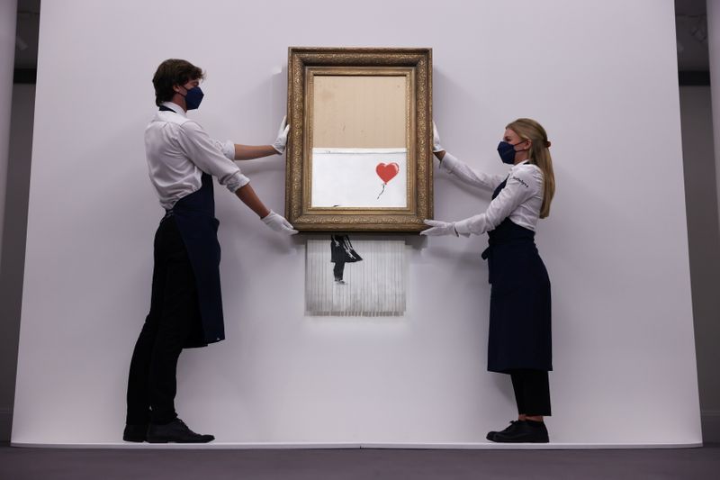 &copy; Reuters. Foto de archivo de asistentes de Sotheby's en Londres posan con 'Love is in the Bin', una obra de Banksy. 
Sep 3, 2021. REUTERS/Tom Nicholson/ 