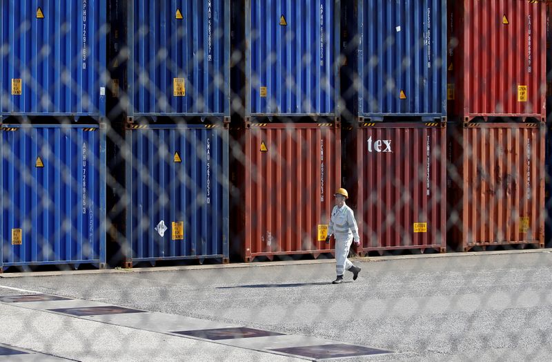 &copy; Reuters. FILE PHOTO: A worker walks between shipping containers at a port in Tokyo, Japan, March 22, 2017. REUTERS/Issei Kato