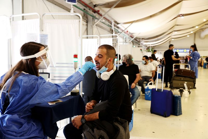 &copy; Reuters. FILE PHOTO: A healthcare worker takes a swab sample from a traveller for a coronavirus disease (COVID-19) test at the Ben Gurion International Airport in Lod, near Tel Aviv, Israel October 13, 2021. REUTERS/ Ronen Zvulun/File Photo