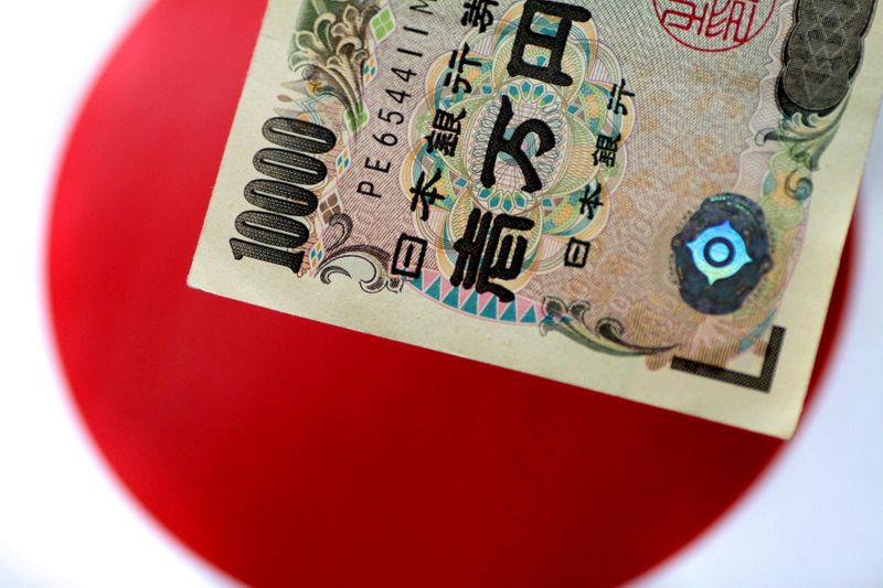 &copy; Reuters. Una banconota da 10000 yen su una bandiera giapponese. REUTERS/Thomas White