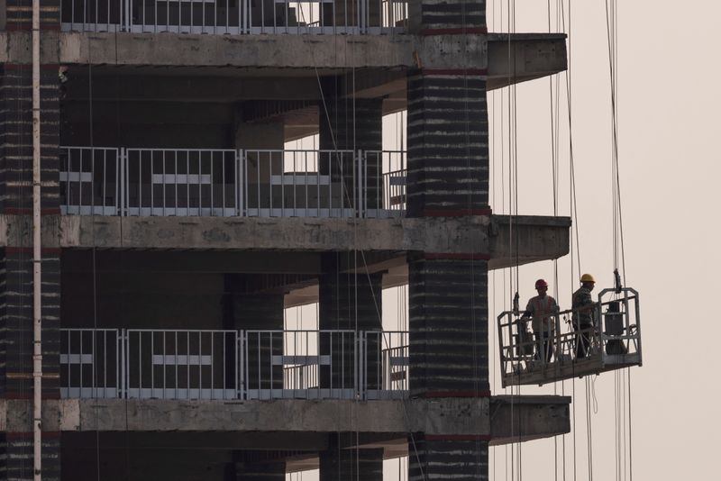 © Reuters. Men work at the construction site of a highrise building in Beijing, China, October 18, 2021.   REUTERS/Thomas Peter