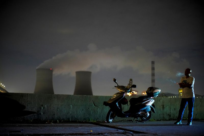 &copy; Reuters. رجل يدخن قرب محطة كهرباء تعمل بالفحم في شنغهاي بالصين يوم 14 أكتوبر تشرين الأول 2021. تصوير: آلي سونج - رويترز 