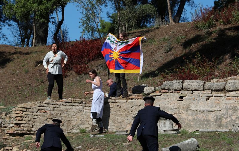 © Reuters. Winter Olympics - Lighting ceremony of the Olympic flame for the Beijing 2022 Winter Olympics - Ancient Olympia, Olympia, Greece - October 18, 2021 A protester holds a Tibetan flag during the Olympic flame lighting ceremony for the Beijing 2022 Winter Olympics REUTERS/Costas Baltas     